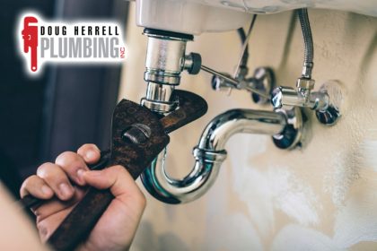 someone fixing a leak with a wrench under sink